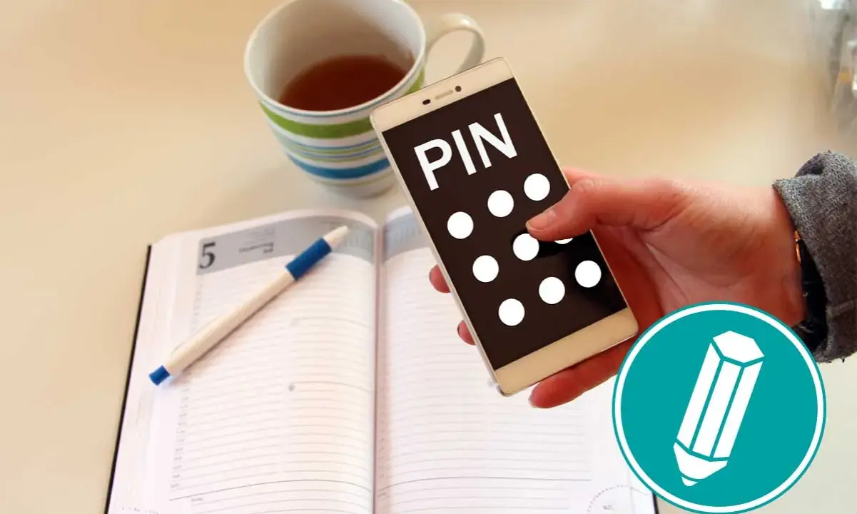 Hand hält Smartphone mit "PIN" und Punkten. Daneben ein Notizbuch mit Stift und eine Tasse Tee. Was ist ein PIN?