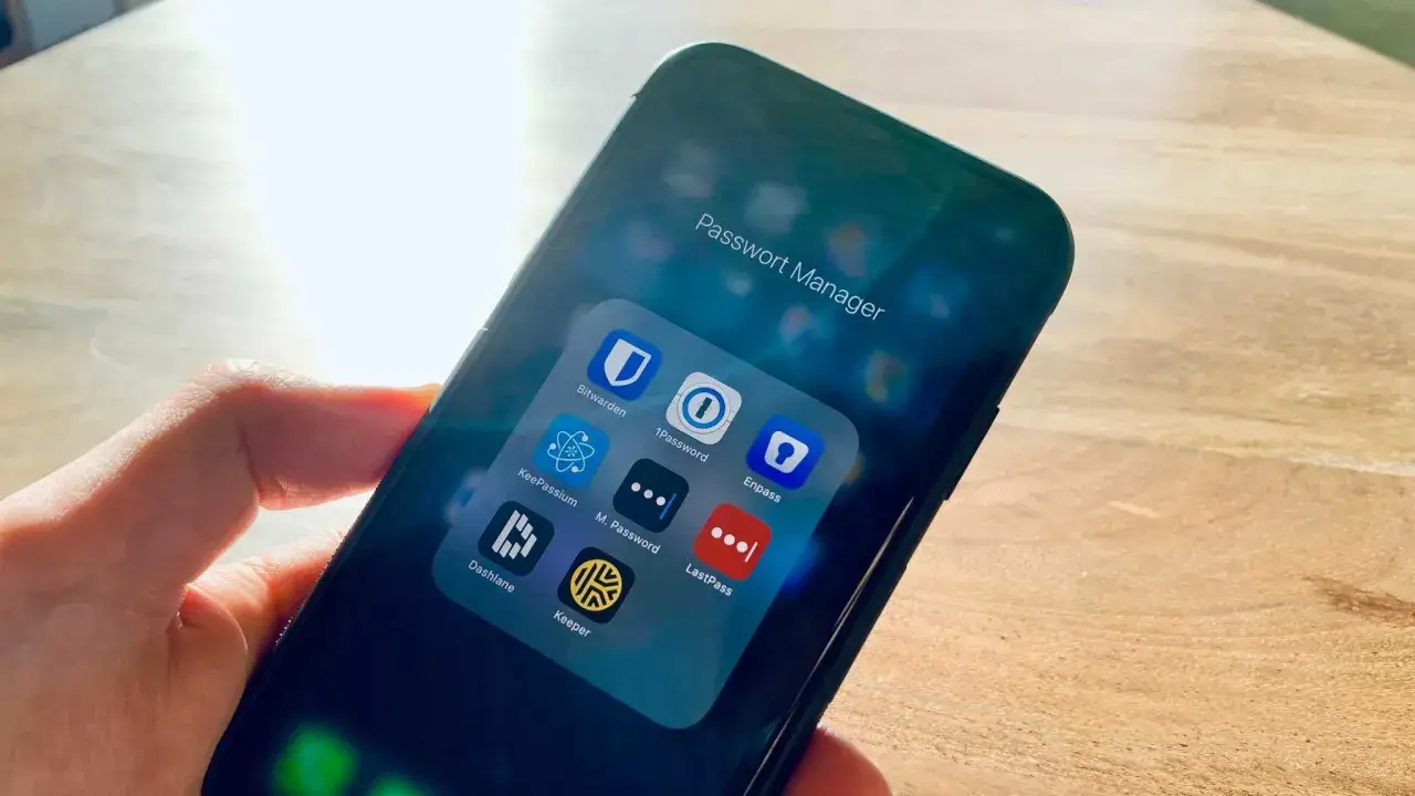 Hand hält Smartphone mit Ordner "Passwort Manager". Darin Apps wie 1Password, Enpass, Dashlane, Keeper – jede eine Bitwarden Alternative.