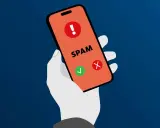 Hand hält Smartphone mit Warnsymbol und "SPAM" Schriftzug. Grüne Haken und rotes Kreuz zeigen Optionen.