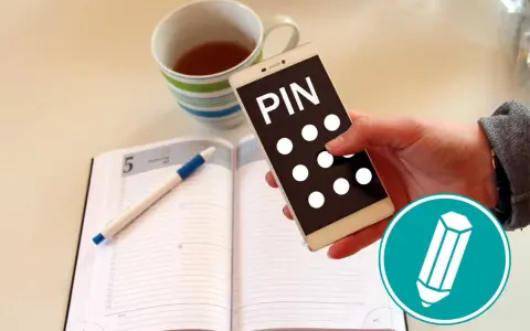 Hand hält Smartphone mit "PIN" und Punkten. Daneben ein Notizbuch mit Stift und eine Tasse Tee. Was ist ein PIN?